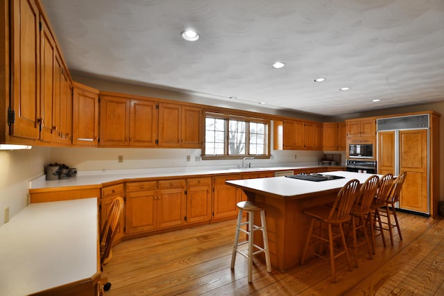 8871 Patterson Rd, Hilliard, OH 43026 - kitchen featuring black appliances, recessed lighting, a kitchen bar, a center island, and light wood-style floors
