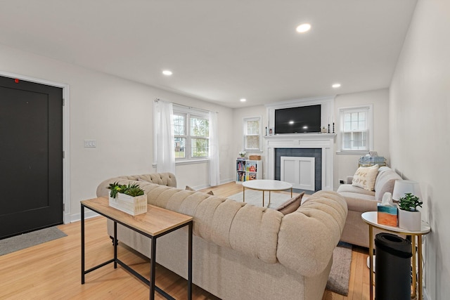 living room featuring recessed lighting, baseboards, a tile fireplace, and light wood finished floors