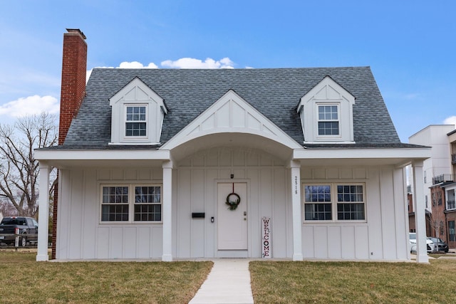 cape cod home featuring board and batten siding, roof with shingles, a chimney, and a front lawn