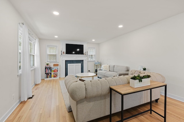 living area featuring light wood-style floors, a fireplace, baseboards, and recessed lighting