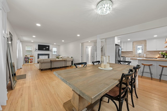 dining space with light wood-type flooring, a fireplace, and recessed lighting