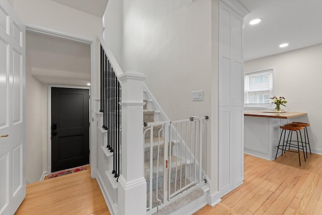 stairs featuring baseboards, wood finished floors, and recessed lighting