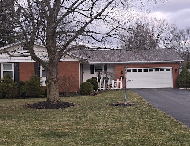 ranch-style home with driveway, brick siding, and a front yard