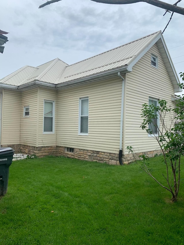 view of side of property with a lawn and metal roof