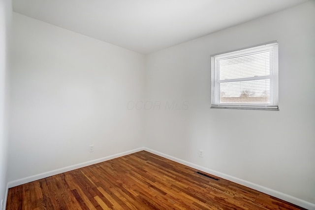 unfurnished room with visible vents, baseboards, and wood finished floors