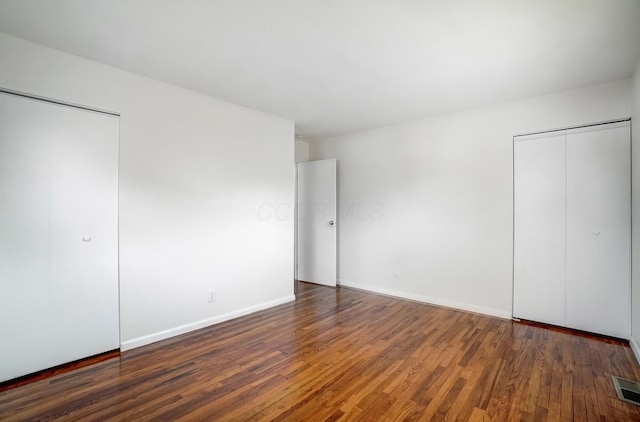 unfurnished bedroom featuring visible vents, wood finished floors, and baseboards