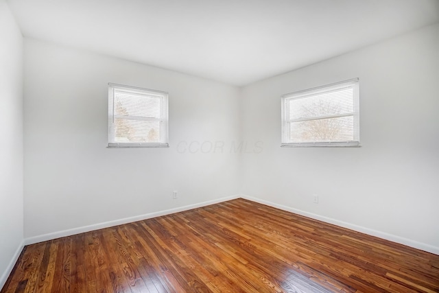 unfurnished room featuring plenty of natural light, baseboards, and wood finished floors