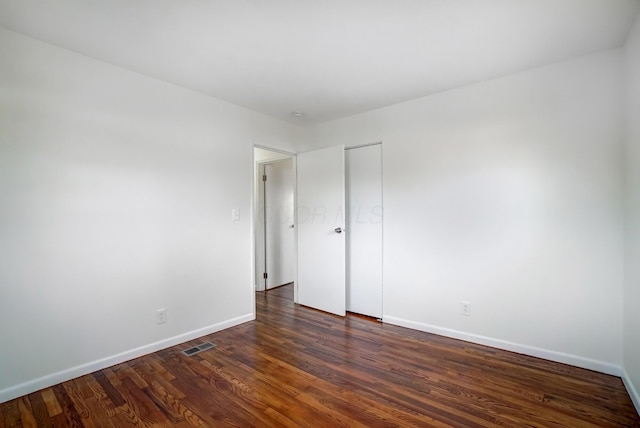 empty room with visible vents, baseboards, and dark wood-style floors