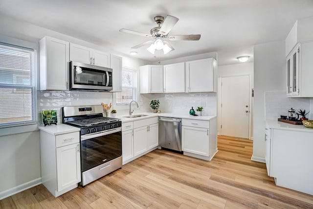 kitchen with a sink, white cabinets, light wood-style floors, and stainless steel appliances