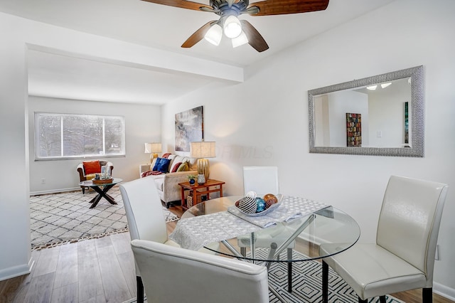 dining space featuring beam ceiling, ceiling fan, baseboards, and wood finished floors