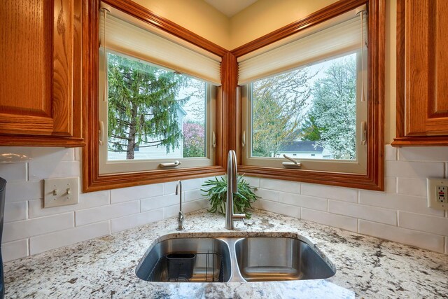 7334 Crossett Ct, Canal Winchester, OH 43110 - details featuring brown cabinetry, tasteful backsplash, a sink, and light stone counters