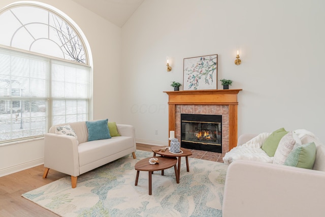 living room with lofted ceiling, a fireplace, baseboards, and wood finished floors