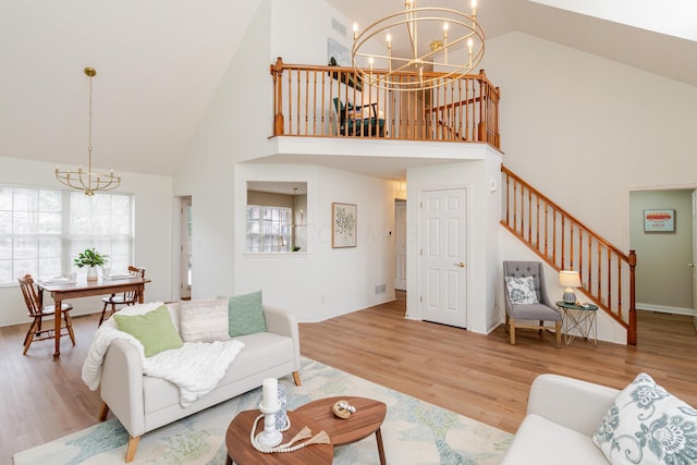 living room featuring baseboards, stairway, a notable chandelier, and wood finished floors