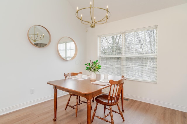 dining area featuring an inviting chandelier, light wood-style flooring, and baseboards