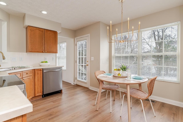 kitchen featuring light countertops, decorative backsplash, a sink, light wood-type flooring, and dishwasher