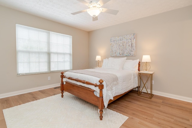 bedroom with a textured ceiling, baseboards, and wood finished floors