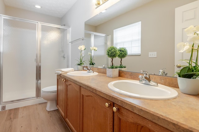 full bathroom featuring a stall shower, a sink, a textured ceiling, and wood finished floors