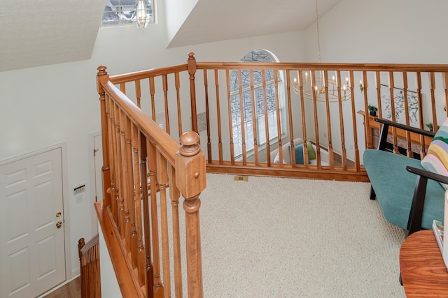 stairs featuring a chandelier, lofted ceiling, and carpet floors