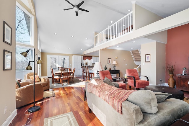 living area with a ceiling fan, wood finished floors, recessed lighting, a high ceiling, and stairs