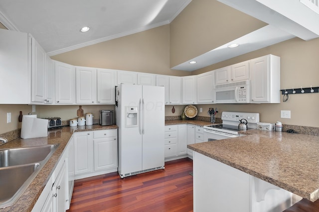 kitchen with a sink, white appliances, a peninsula, dark wood-style flooring, and vaulted ceiling