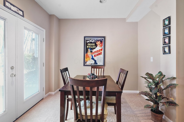 dining area with light colored carpet, baseboards, and french doors