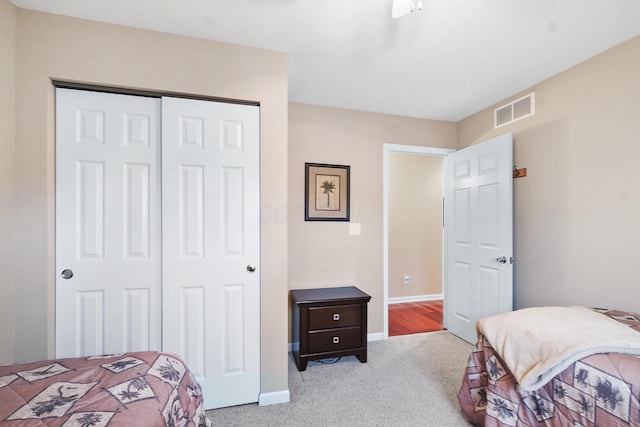 carpeted bedroom featuring a closet, visible vents, and baseboards