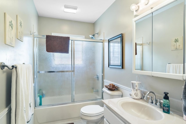 full bath with toilet, vanity, and shower / bath combination with glass door