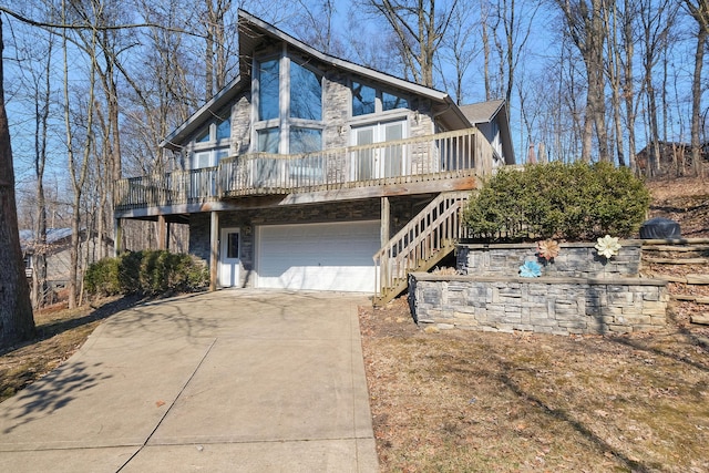 view of front of property featuring stairway, an attached garage, stone siding, and driveway