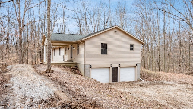 view of front facade featuring a garage, driveway, a shingled roof, and a porch