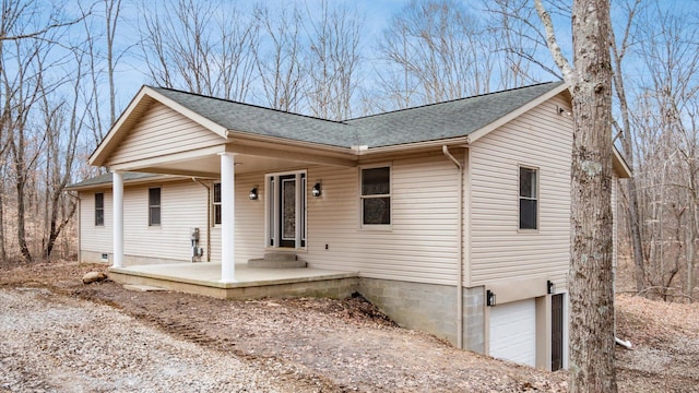 ranch-style house with an attached garage, covered porch, and a shingled roof