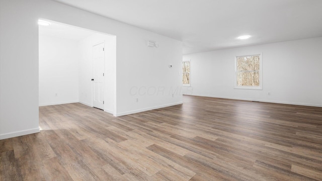 spare room featuring baseboards and wood finished floors