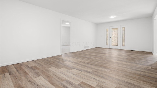 spare room with wood finished floors, visible vents, and baseboards