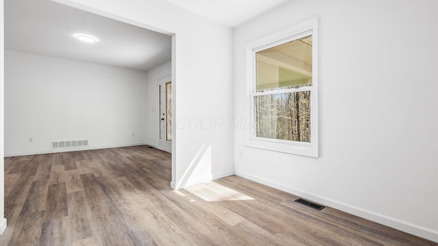 unfurnished room with wood finished floors, visible vents, and baseboards