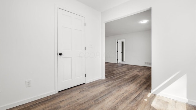 unfurnished room with wood finished floors, visible vents, and baseboards