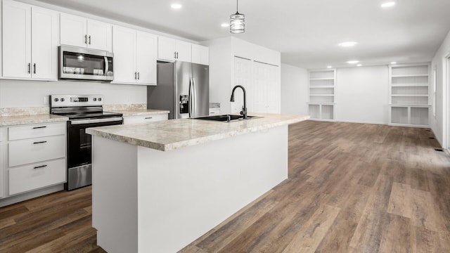 kitchen featuring dark wood-style flooring, a center island with sink, appliances with stainless steel finishes, white cabinets, and a sink