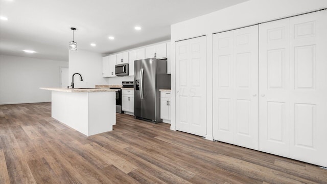 kitchen featuring white cabinets, an island with sink, dark wood-style flooring, stainless steel appliances, and a sink