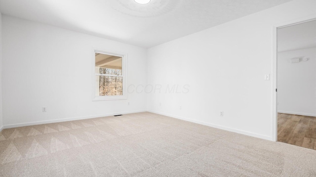 empty room featuring carpet and baseboards