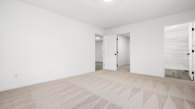 unfurnished bedroom featuring carpet floors, a walk in closet, connected bathroom, and baseboards