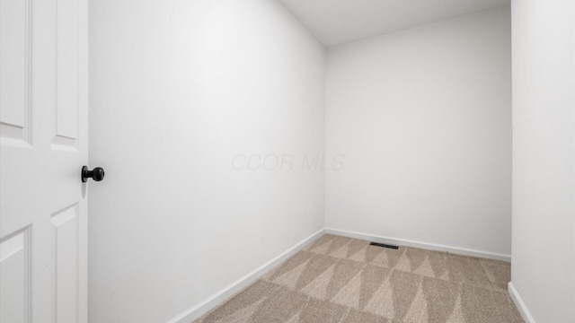 unfurnished room with baseboards and light colored carpet