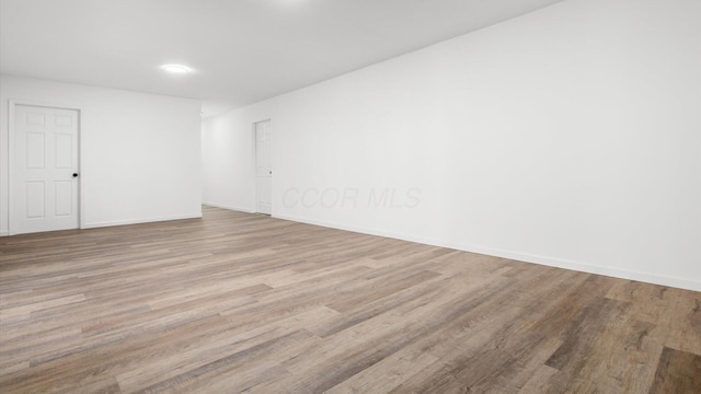 spare room featuring baseboards and wood finished floors