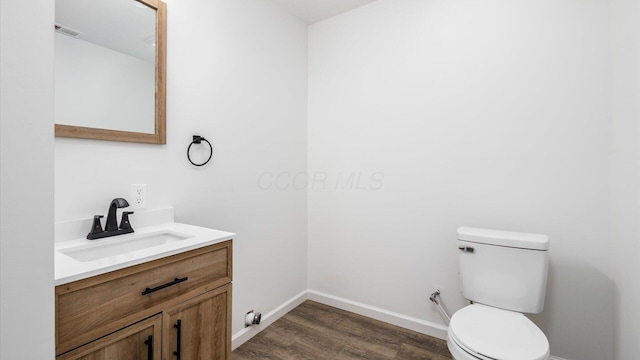 bathroom with visible vents, toilet, vanity, wood finished floors, and baseboards