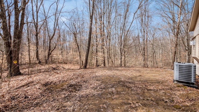 view of yard featuring a forest view and central AC unit