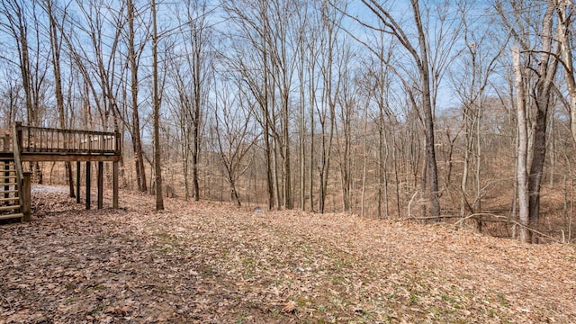 view of yard featuring stairway, a view of trees, and a wooden deck