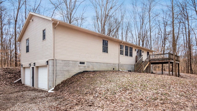 view of side of property with an attached garage, stairs, and a deck