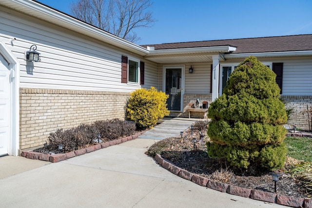 doorway to property featuring concrete driveway and brick siding