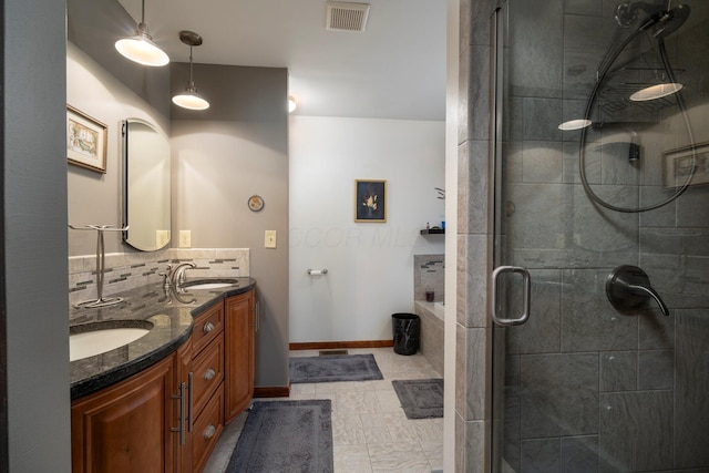 full bath featuring visible vents, a shower stall, double vanity, decorative backsplash, and a sink