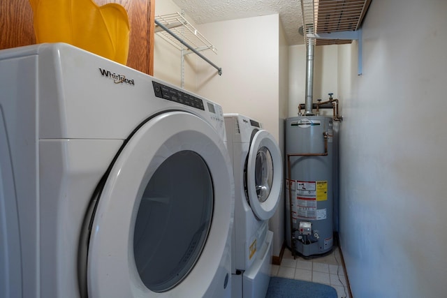 laundry area featuring washer and clothes dryer, water heater, laundry area, light tile patterned flooring, and a textured ceiling