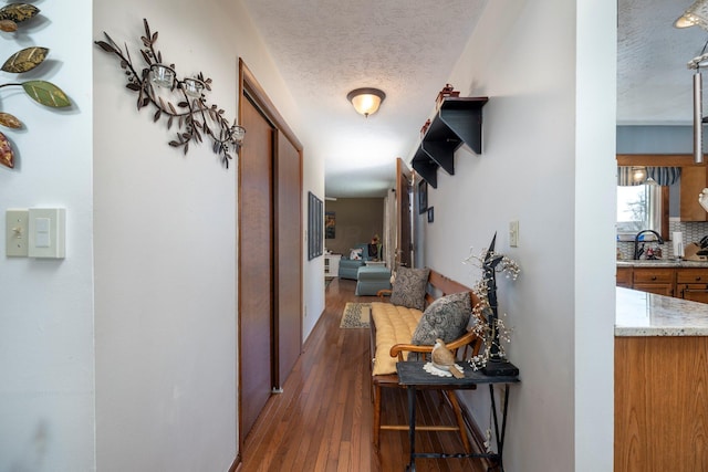 hallway with a sink, wood-type flooring, and a textured ceiling