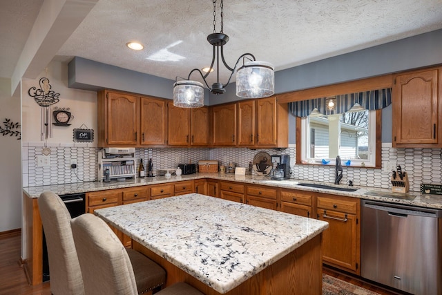 kitchen featuring a sink, brown cabinets, a breakfast bar, and stainless steel dishwasher