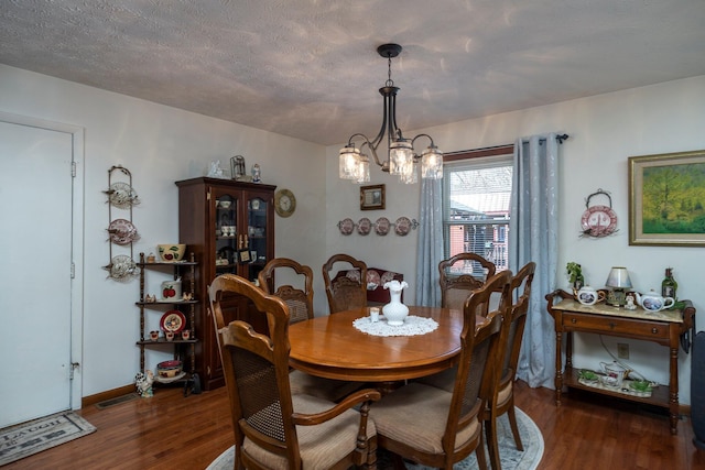 dining room featuring visible vents, a textured ceiling, an inviting chandelier, and wood finished floors